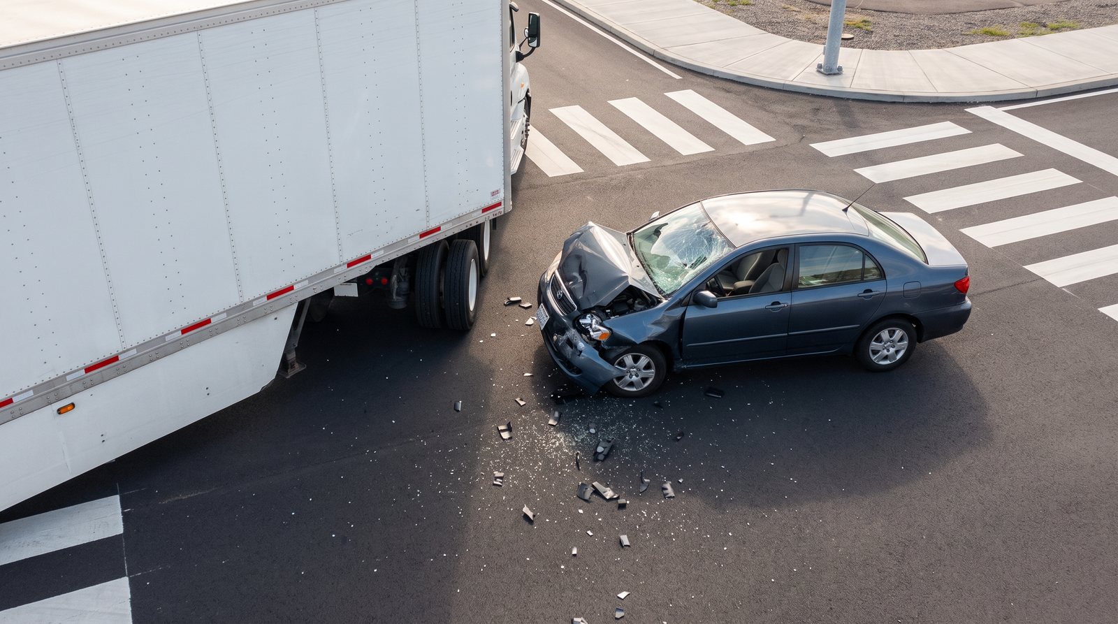 Damage reference: sedan with buckled hood and cracked windshield beside the trailer